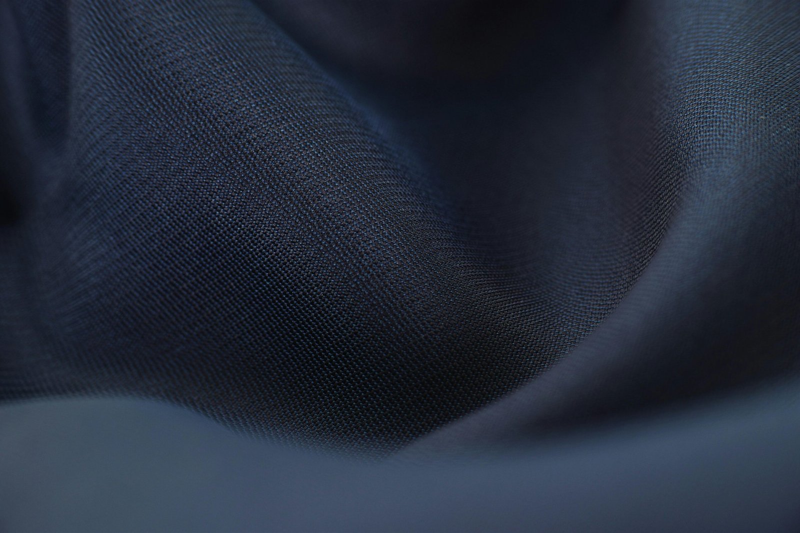 Detailed close-up of woven blue fabric with elegant crumples, highlighting texture and depth.